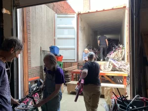 Volunteers carry bikes into a shipping container