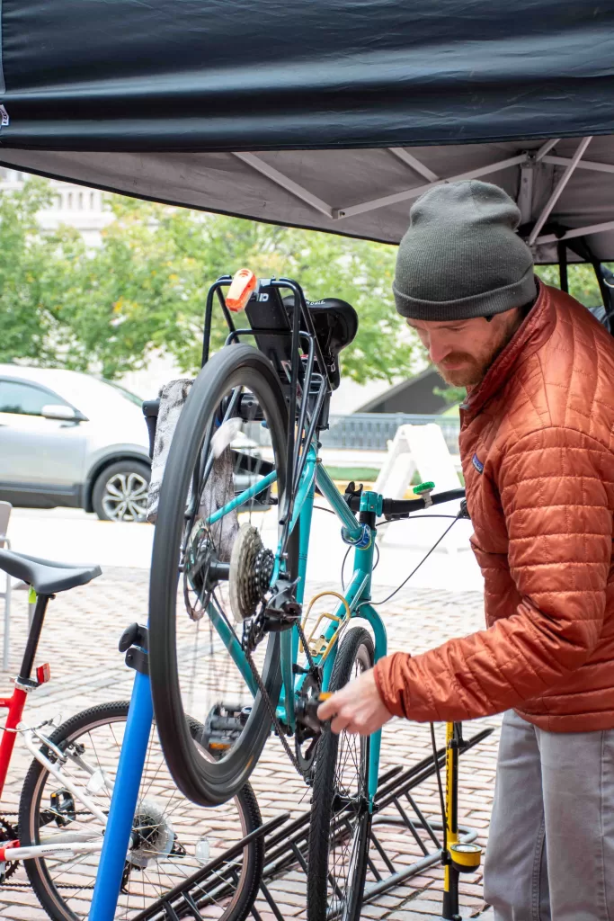 Mechanic working on a bright green bike on a work stand.